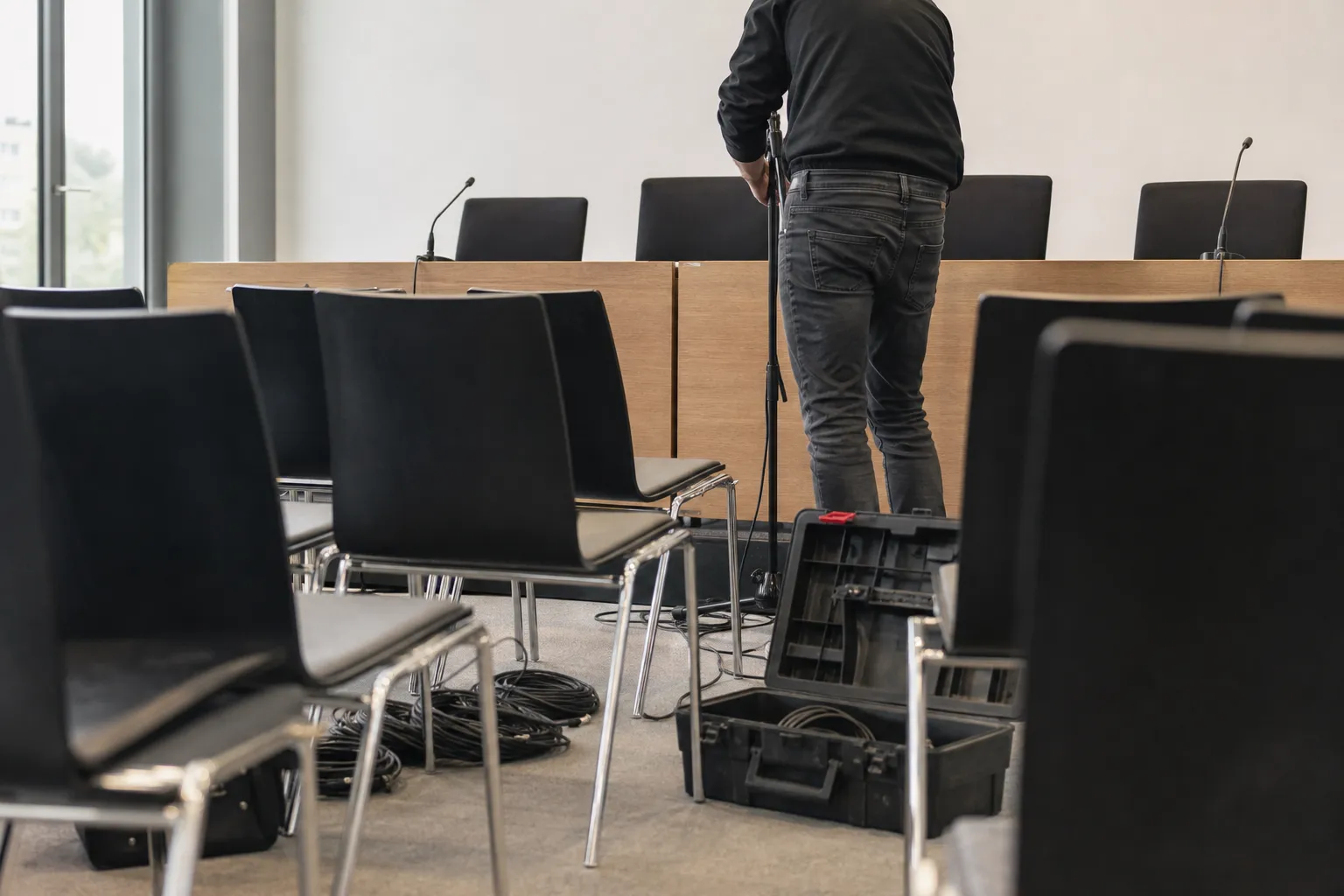 Salle de séminaire en cours d’installation, chaises en alignement et caisse de matériel ouverte au sol